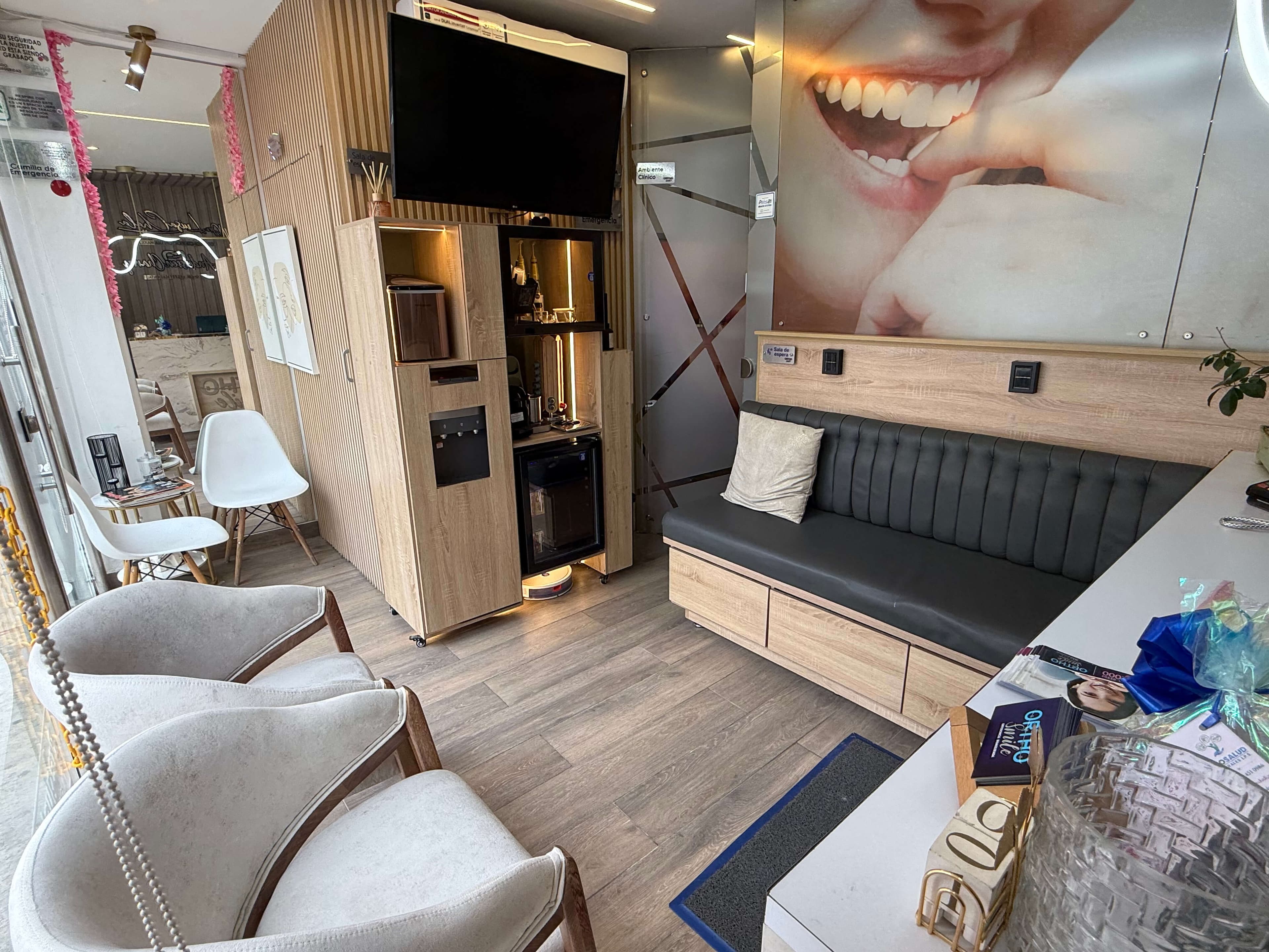 Sala de espera de OrthoSmile con poltronas, televisor y estación de bebidas